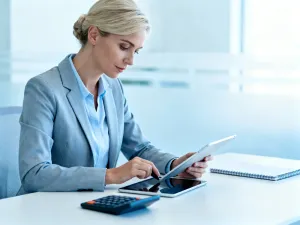 Laptop z prostym kalkulatorem wynagrodzeń na jasnym biurku w domowym biurze, obok notes i długopis, jasne, spokojne wnętrze.